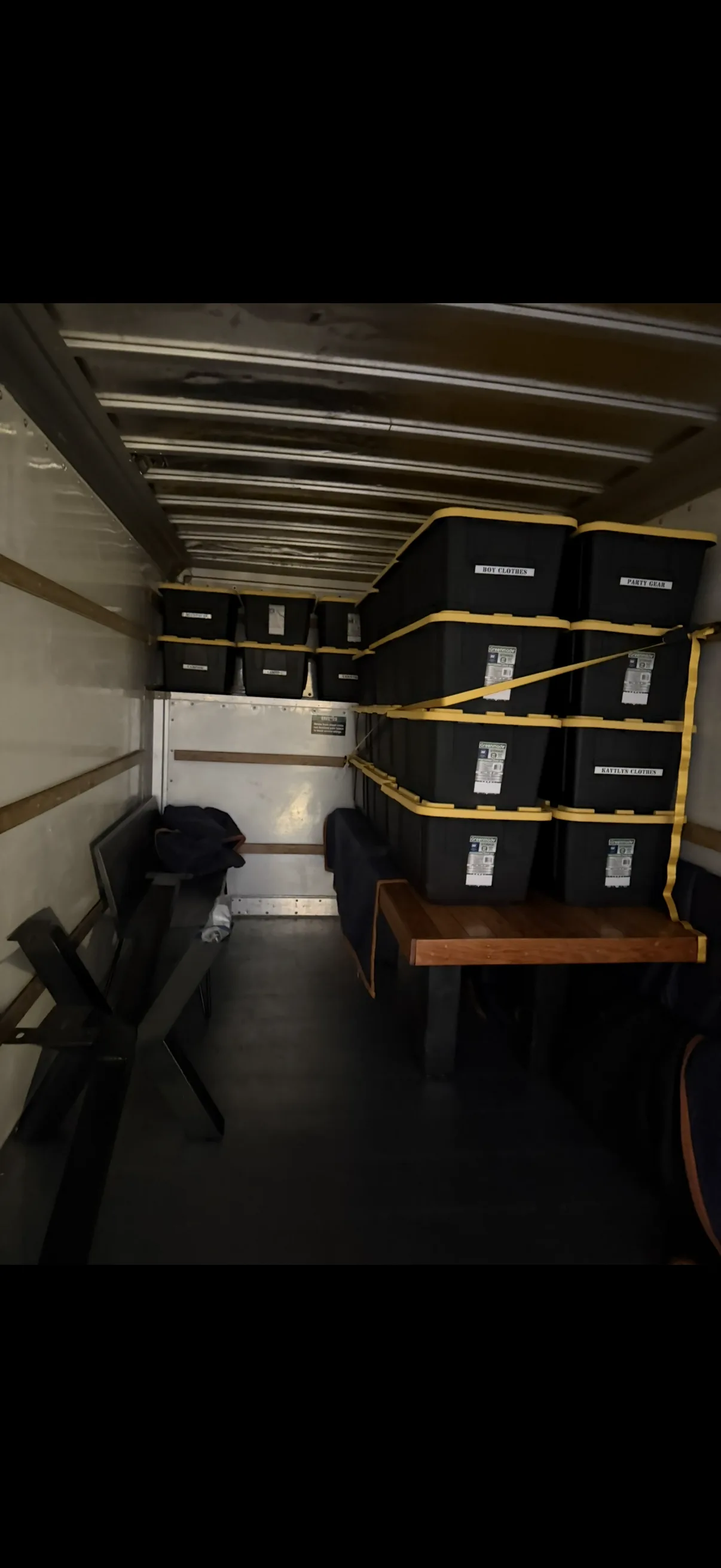 Moving truck interior with bins and items secured with straps